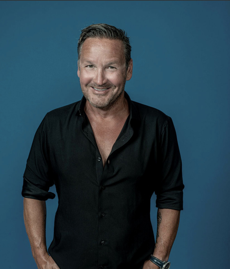 Mann i svart skjorte smiler